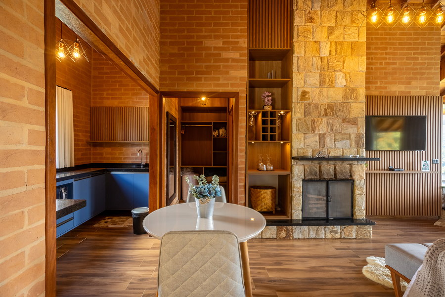 Stone fireplace with open mesh doors, a fire burning inside, two glasses of red wine and a wooden platter with cheese and crackers on the hearth.